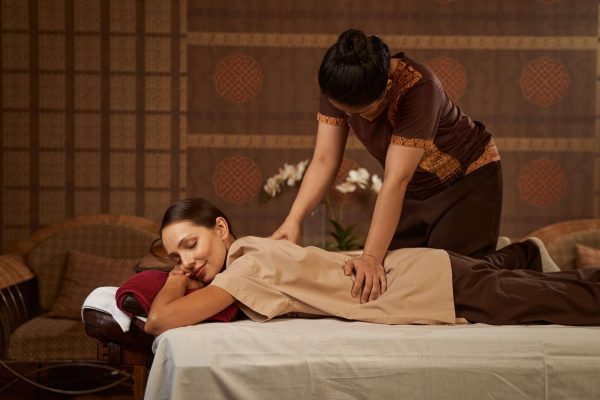 Experienced massotherapist giving female patient Thai massage